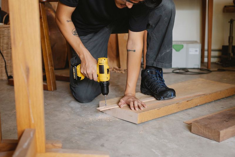 a handyman repairing a cabinet door with a drill